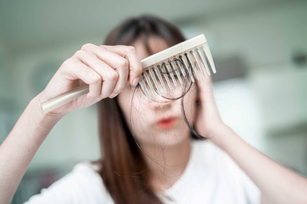 A woman shows her brush with lots of hair in it in.