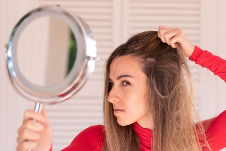 Woman checks her hair in the mirror.