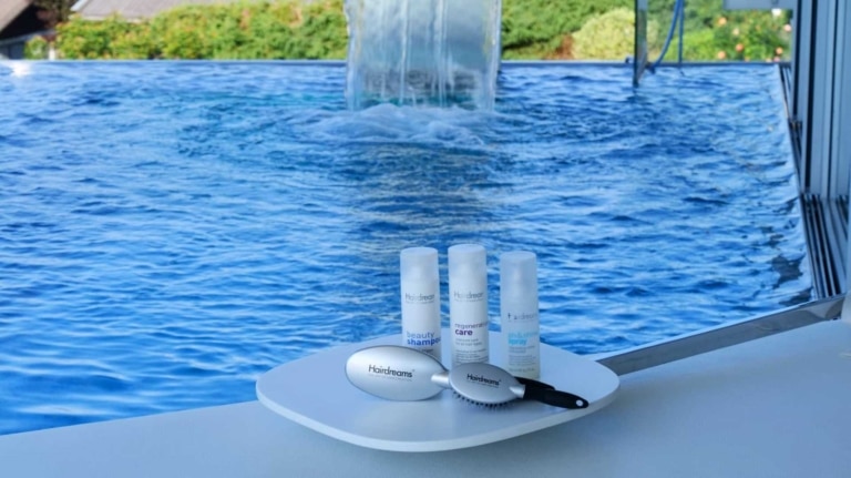 Care products on a table in front of a swimming pool