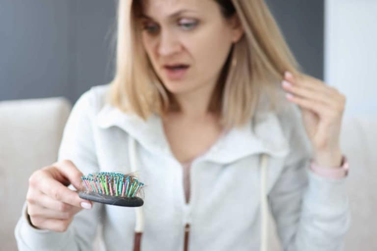 Woman looks surprised at hair in brush