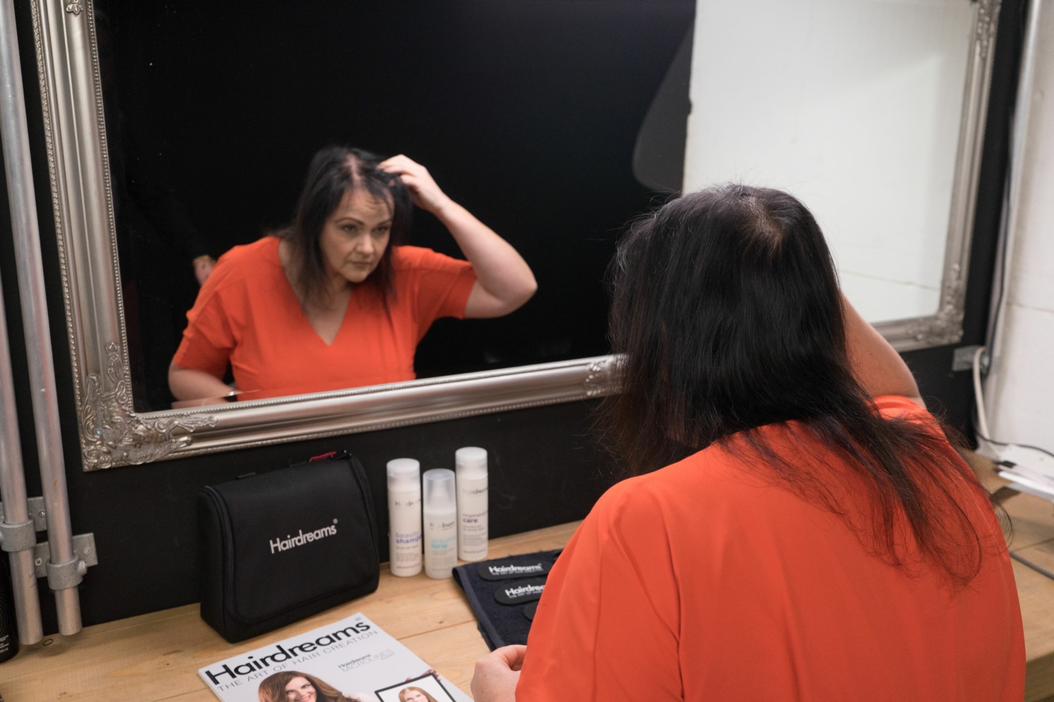 Woman checks her thin hair in the mirror.